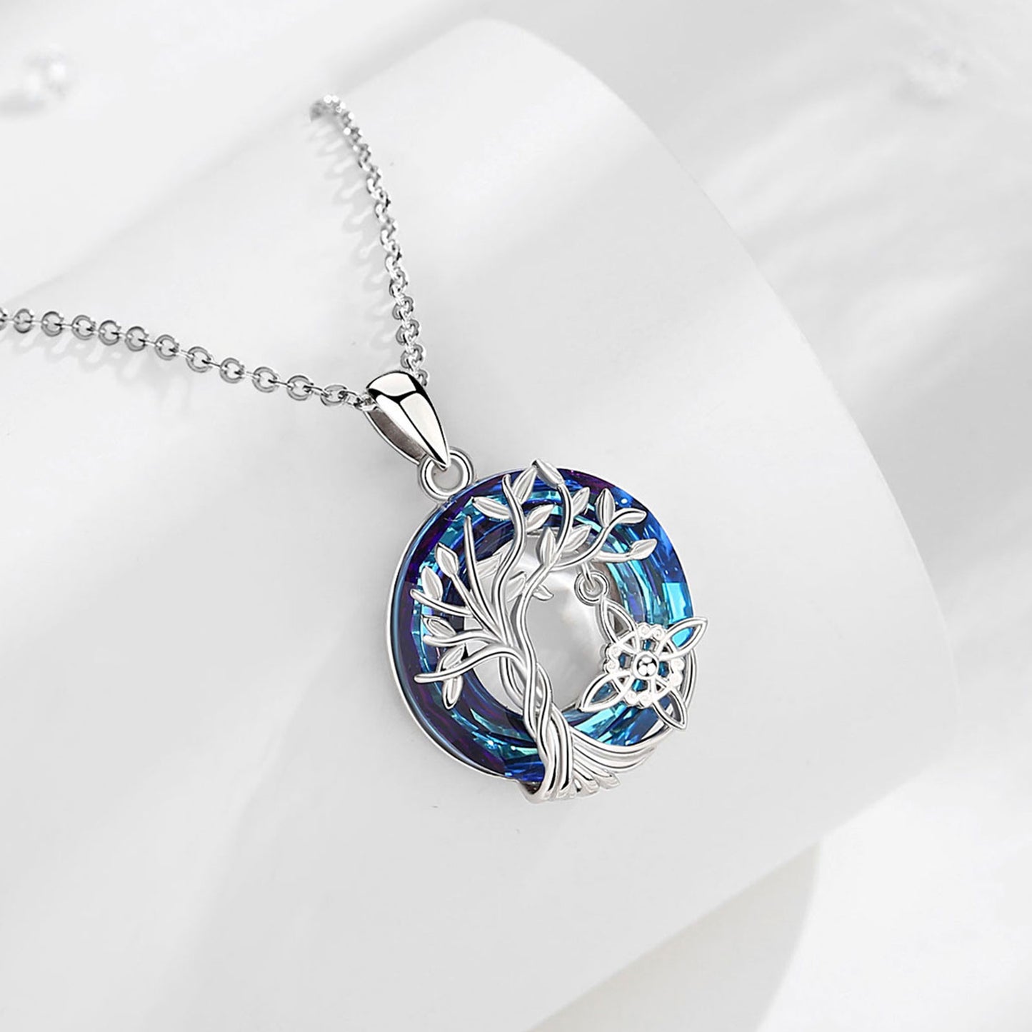 Sterling silver Witch Knot Tree of Life amulet necklace with a vibrant blue crystal pendant.