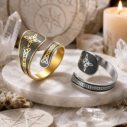 Gold and silver Celtic Witch Knot rings displayed on marble with pentacle wood coasters, quartz crystals, and candlelight