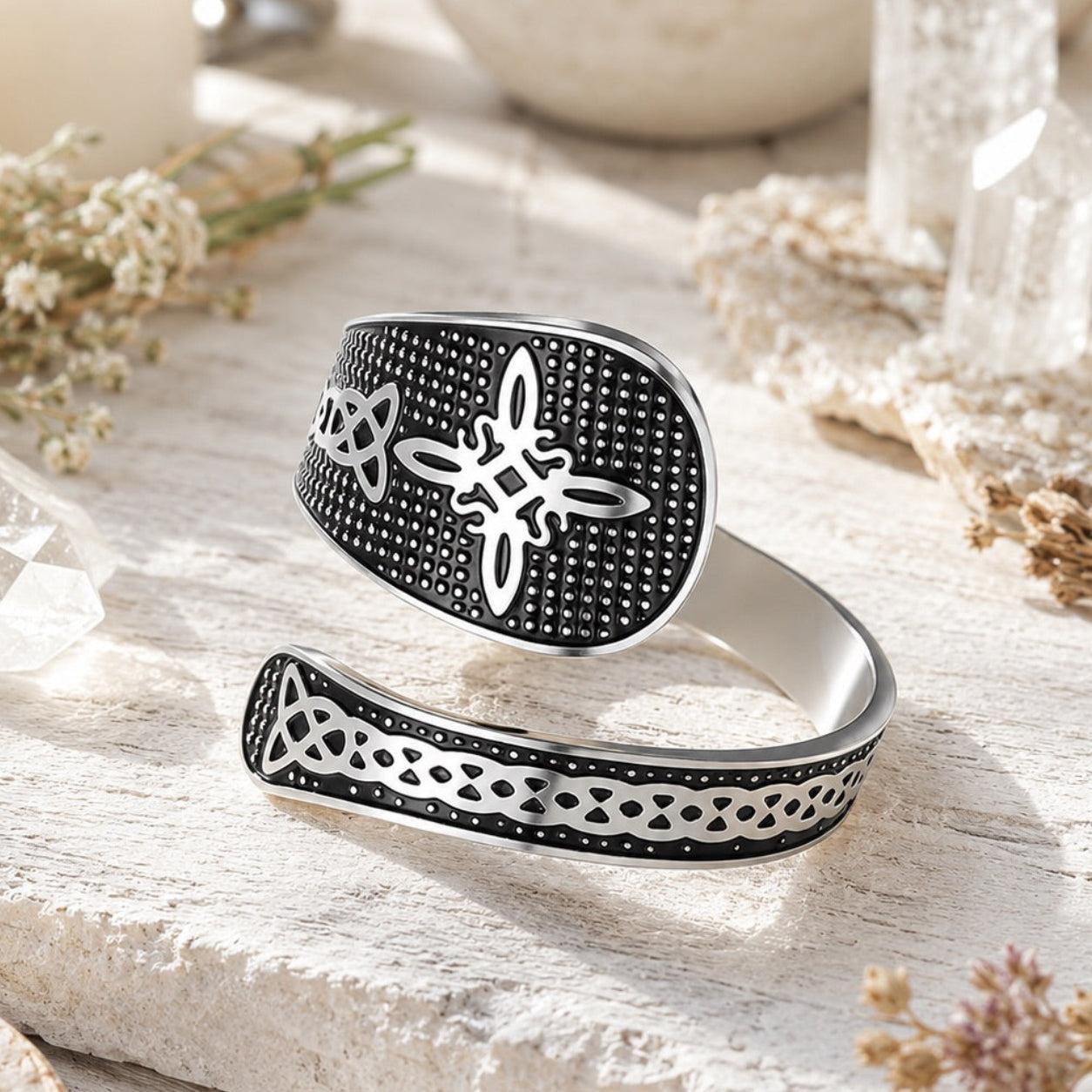 Close-up of silver Witch Knot open ring showing Celtic trinity and endless knot engravings on a textured black band