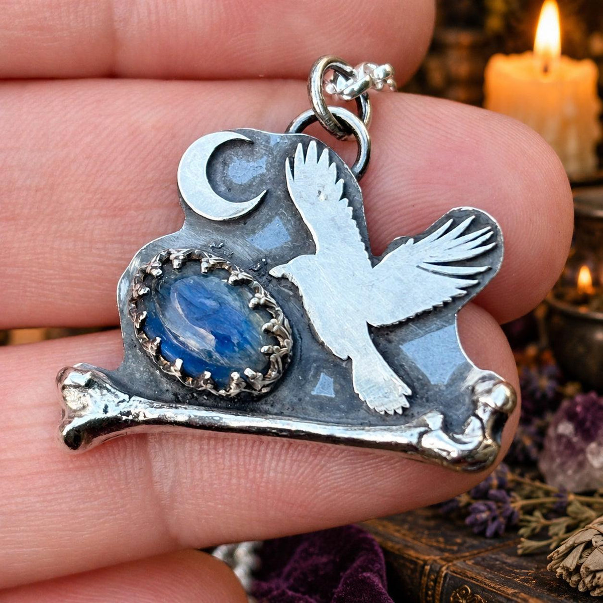Crow and crescent moon pendant necklace with blue kyanite on a bone, held in hand - witchy jewelry