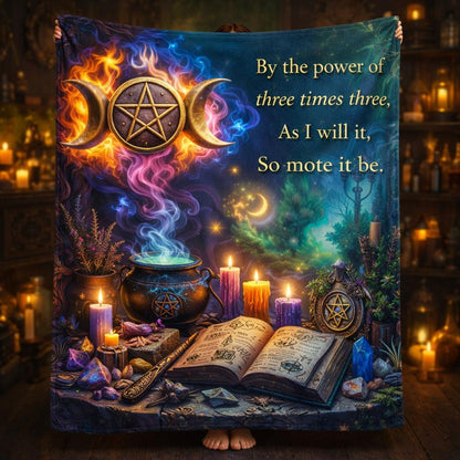 Dark blue fleece blanket with glowing triple moon, pentagram, cauldron, candles, and "So mote it be" text.