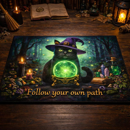 Witchy black cat doormat with a purple hat, green crystal ball, and "Follow your own path" text in a dark forest.
