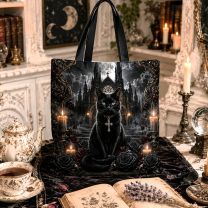 A black tote bag featuring a gothic illustration of a black cat in a dark castle, styled in a cozy, vintage-inspired room with candles, books, and a teapot.