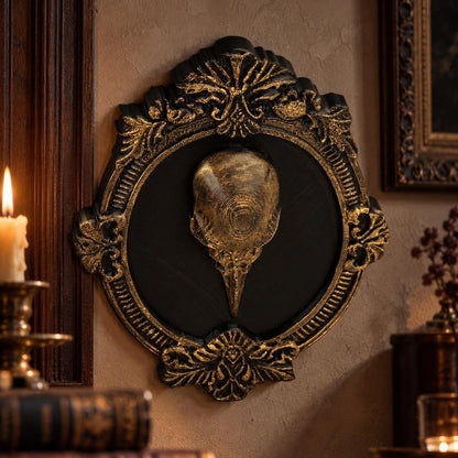 Angled view of accented skull relief: Gothic Raven Skull Wall Plaque, featuring a raven skull relief surrounded by an elaborate oval frame.