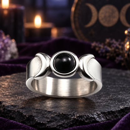 Silver Triple Moon Goddess ring with black onyx and crescent details on a dark Wiccan altar