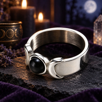 Silver Triple Moon Goddess ring with black onyx and crescent details on a dark Wiccan altar
