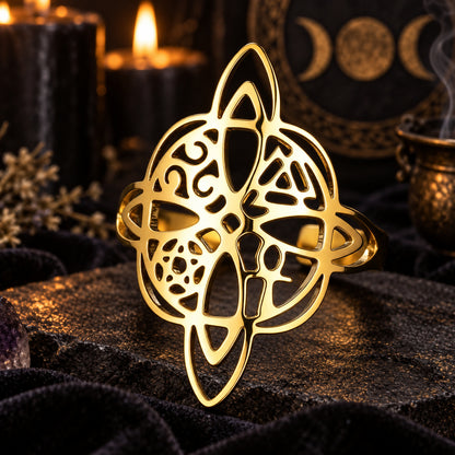 Gold witch knot pagan symbol ring on a dark ritual altar.