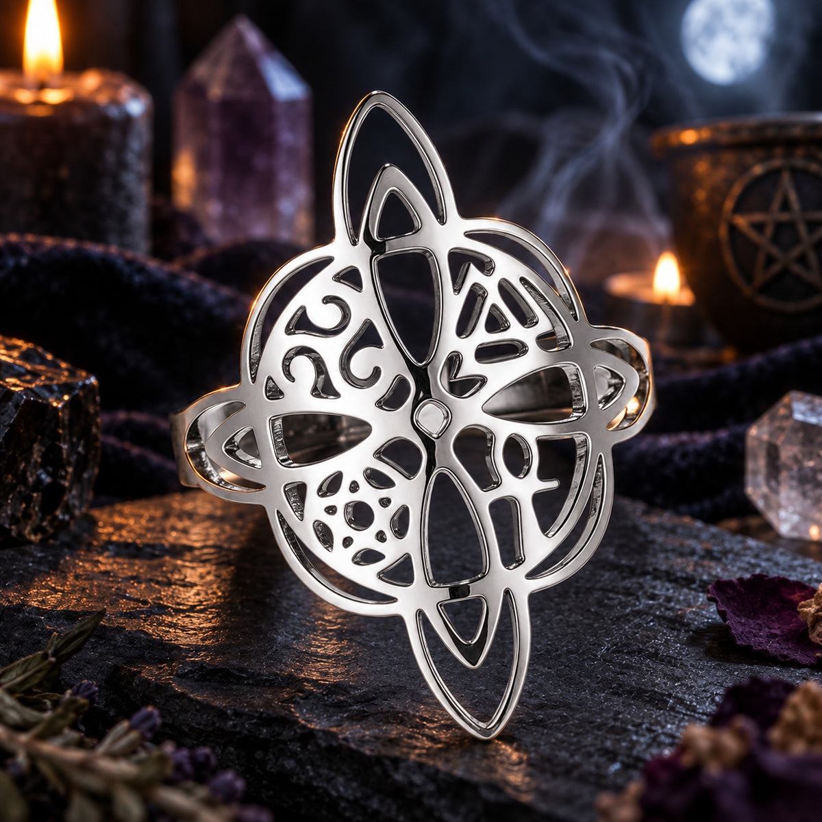 Silver witch knot pagan symbol ring on a dark ritual altar.