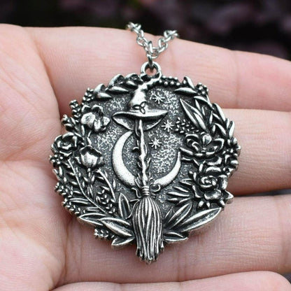 Captivating silver plated Moon Hat Broom Witch Halloween necklace, featuring a crescent moon, witch's hat, and broom, encircled by enchanting floral details.