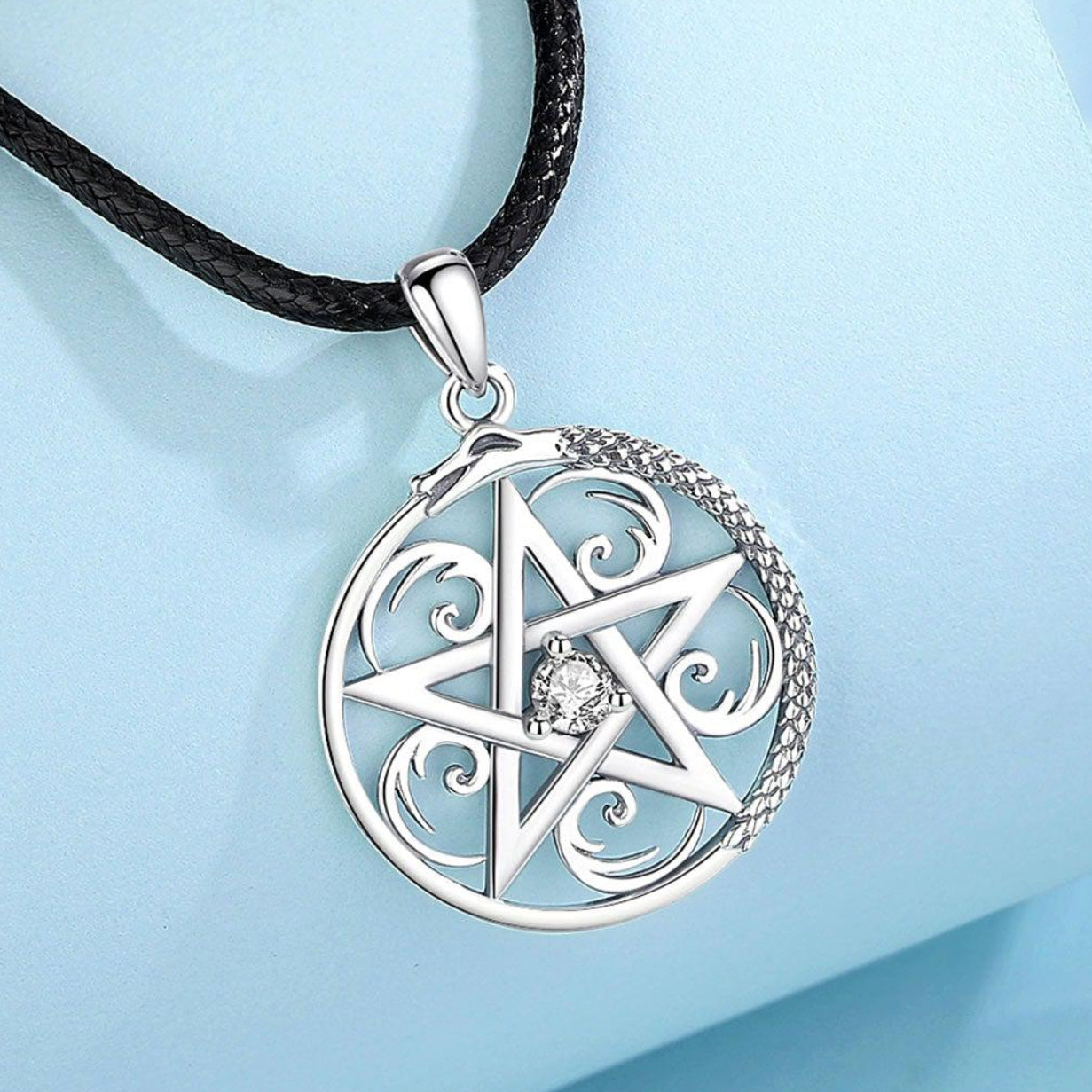 Sterling silver pentacle necklace with a sparkling center stone and intricate snake design on a black cord.