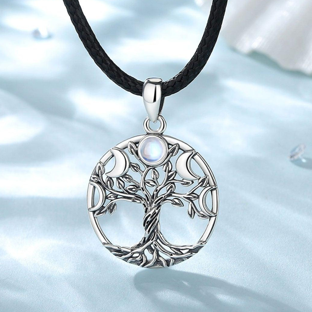 Sterling silver Tree of Life pendant with moon phases and a central iridescent stone on a black cord.